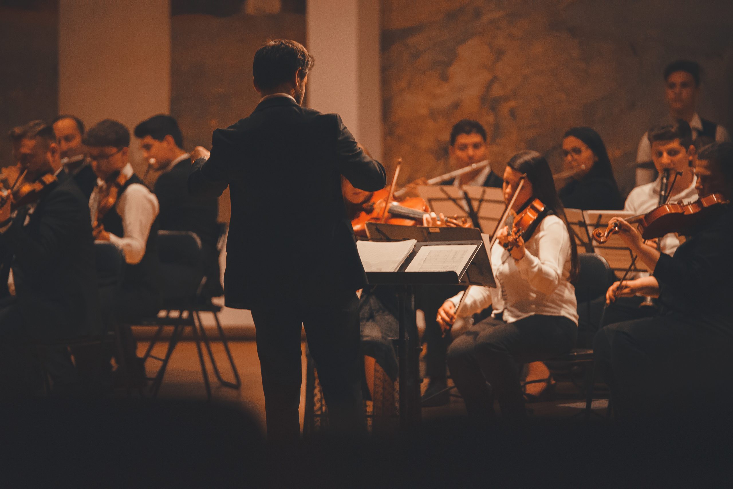 Classical music Orchestra plays with conductor leading the way in the front