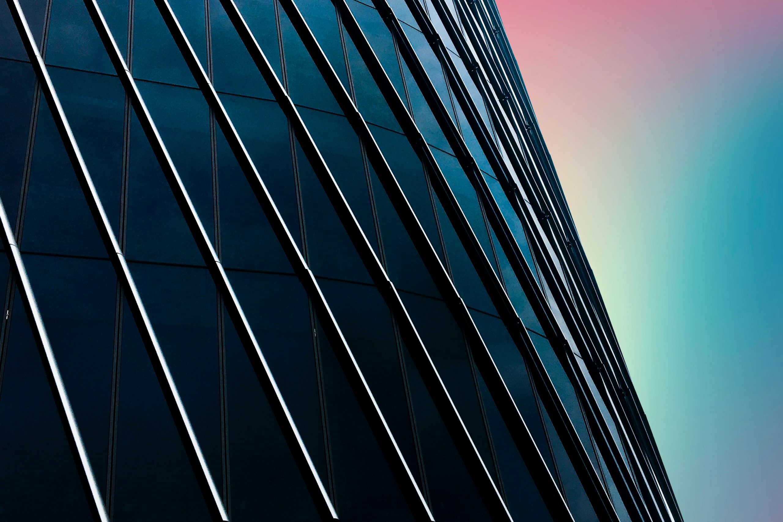 side of large curved skyscraper with rainbow sky in background