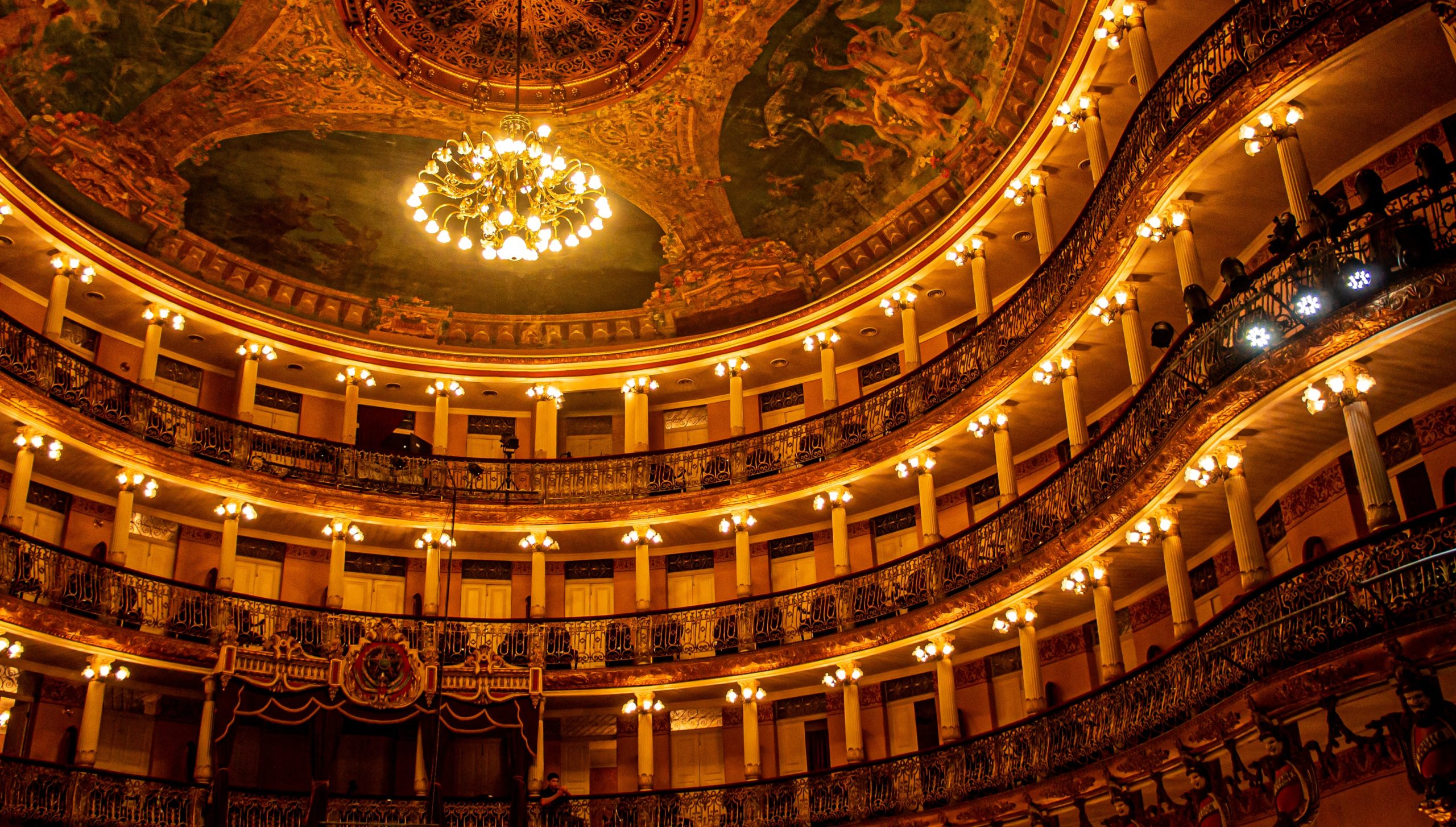 inside of a beautiful opera house with painted ceilings, decorative chandelier, and lights around each seating section