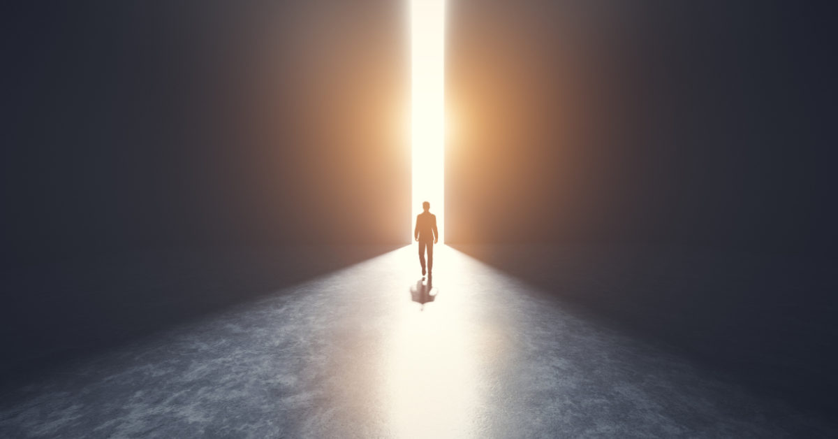 silhouette of a CEO walking out of a dark corridor into a thin pathway of light